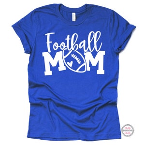 K&ouml;nnte beinhalten: Ein k&ouml;nigsblaues T-Shirt mit dem Text "Football Mom" in Wei&szlig;, mit einer wei&szlig;en Fu&szlig;ballabbildung mit einem Herzen.