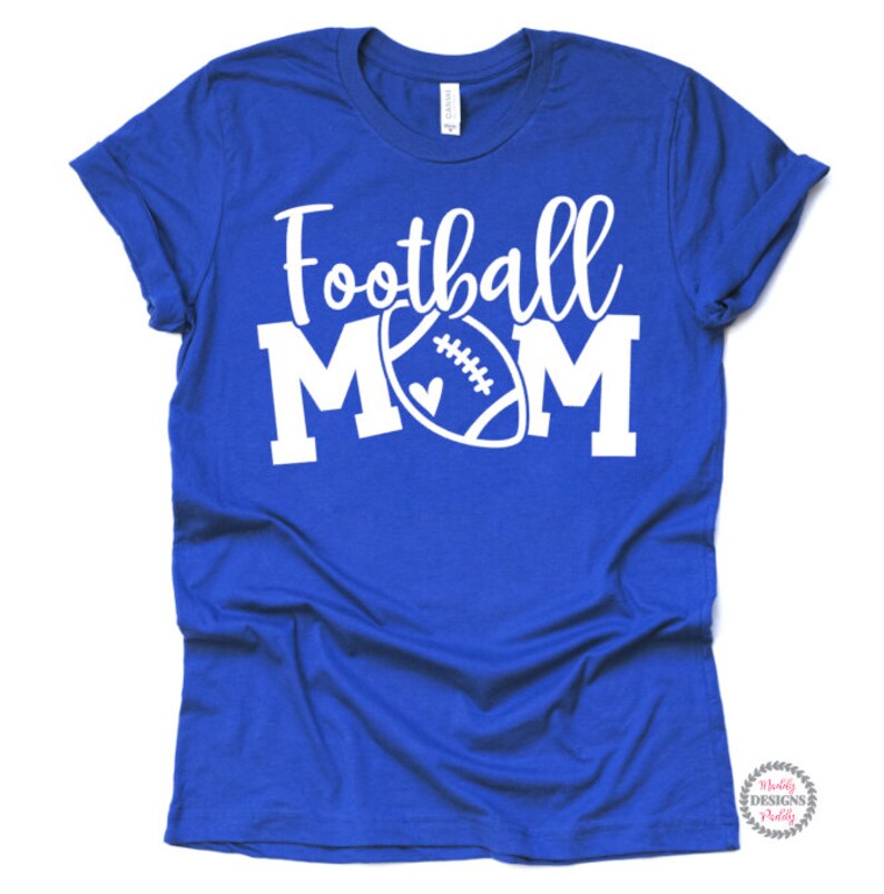 K&ouml;nnte beinhalten: Ein k&ouml;nigsblaues T-Shirt mit dem Text "Football Mom" in Wei&szlig;, mit einer wei&szlig;en Fu&szlig;ballabbildung mit einem Herzen.