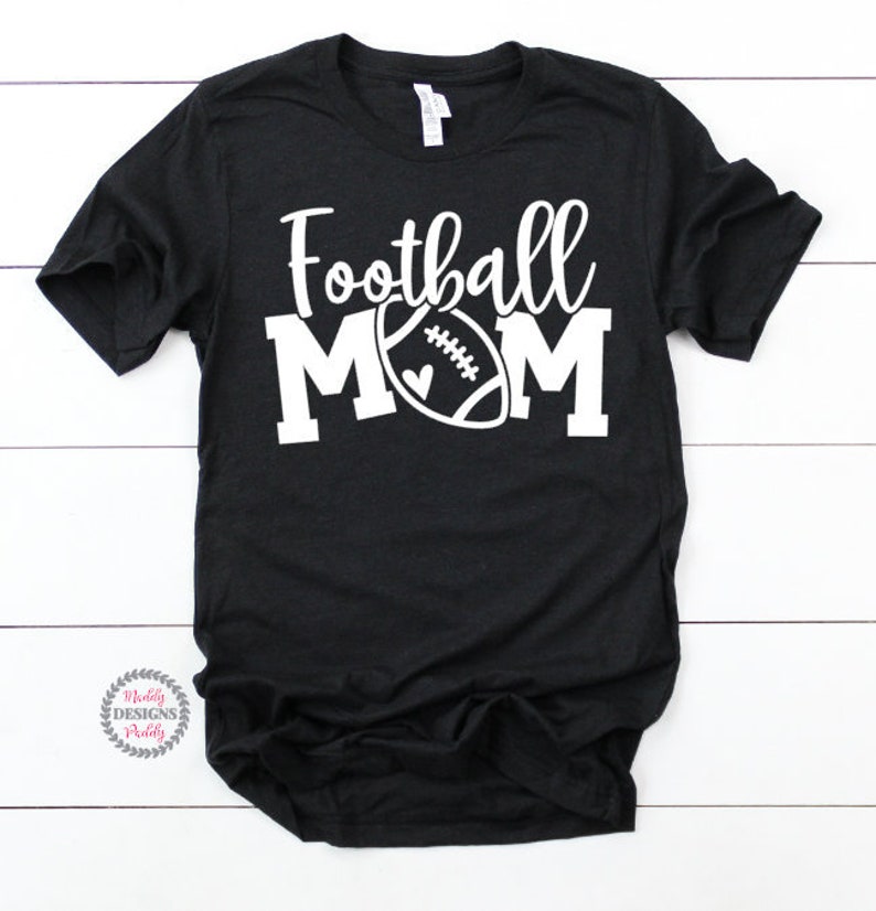 K&ouml;nnte beinhalten: Schwarzes T-Shirt mit wei&szlig;em Text "Football Mom" und einer wei&szlig;en Football-Grafik.