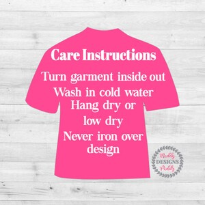 May include: Pink t-shirt with white text outlining care instructions for the garment. The text reads: "Care Instructions Turn garment inside out Wash in cold water Hang dry or low dry Never iron over design".