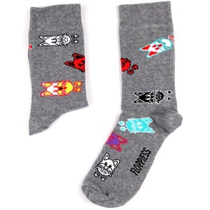 Peut inclure: Une paire de chaussettes grises avec un motif de chat coloré. Les chaussettes ont le mot "Floppiess" imprimé sur l'une d'elles.