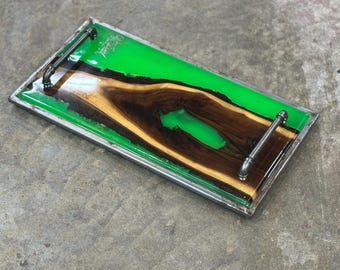 May include: A rectangular serving tray with a green epoxy resin top and a natural wood inlay. The tray has two metal pipe handles on the sides.