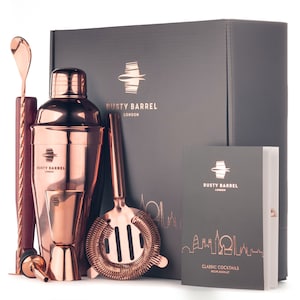 Op de afbeelding: Koperen cocktailshakerset met een receptenboekje. De set bevat een shaker, zeef, maatbeker, barlepel en muddler. De doos is grijs met het Rusty Barrel London logo.