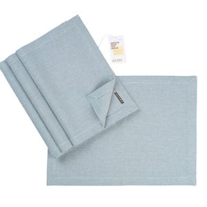 May include: Set of four light blue placemats made of woven fabric. The placemats are folded and stacked on top of each other. The placemats have a subtle texture and a slightly frayed edge.