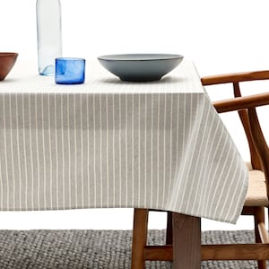 May include: A gray and white striped tablecloth with a wooden table and chair. The table has a blue bowl and a wooden bowl on it.