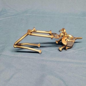 May include: A silver metal sculpture of a dog made from nuts and bolts.