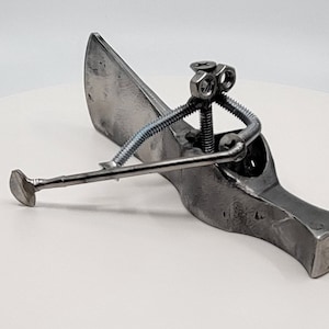 May include: A metal sculpture of a person holding a golf club, made from recycled metal parts, including nuts, bolts, and screws.