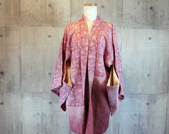 May include: A pink and white patterned Japanese kimono with a traditional design. The kimono is displayed on a mannequin against a concrete wall.