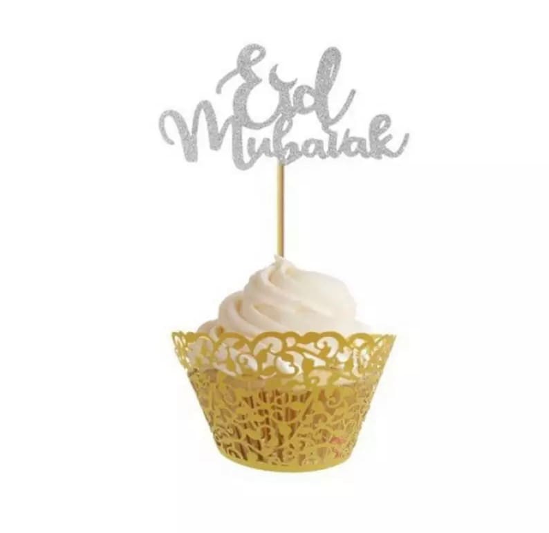 May include: A gold cupcake liner with a white cupcake topped with a silver glitter "Eid Mubarak" cake topper.