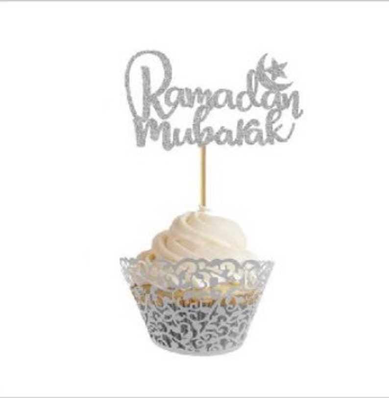 May include: Silver glitter cupcake topper with the text "Ramadan Mubarak" and a crescent moon and star.
