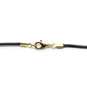 May include: A black leather cord necklace with a gold-toned lobster clasp.