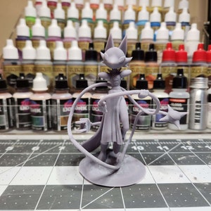 Op de afbeelding: Een grijs 3D-geprint miniatuur van een fantasy-personage met een vossenkop, die een lange robe draagt en een staf met een stervormige top vasthoudt. Het miniatuur staat op een ronde basis.