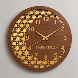 Peut inclure: Une horloge murale circulaire avec un cadre en bois brun foncé et une découpe en forme de croissant de lune. Le fond présente un motif en treillis métallique doré. Le cadran affiche des chiffres dorés de 1 à 12 et le texte MARKAPOLIN en doré.