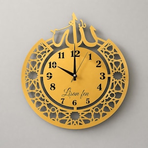 Peut inclure: Une horloge murale circulaire dorée avec une bordure en treillis géométrique complexe et une calligraphie arabe au sommet. Le cadran affiche des chiffres arabes noirs de 1 à 12, des aiguilles noires et le texte Lisan fen en écriture cursive.