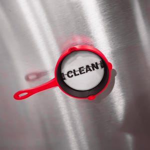 May include: A red and black pan with a white circle in the center that says "CLEAN" in black letters.
