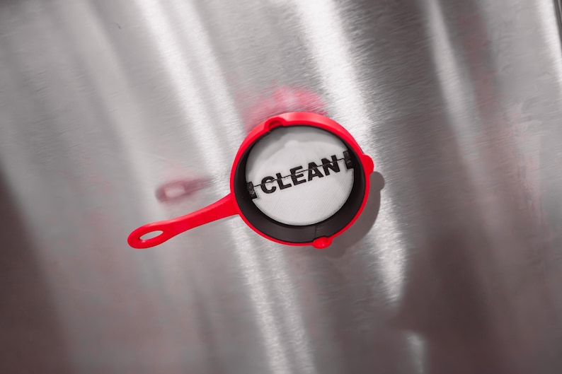May include: A red and black pan with a white circle in the center that says "CLEAN" in black letters.