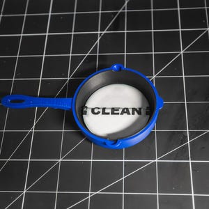 May include: A blue plastic pan with a black interior and a white sticker that says "CLEAN" on it.
