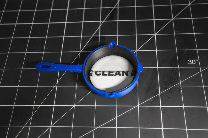 May include: A blue plastic pan with a black interior and a white sticker that says "CLEAN" on it.