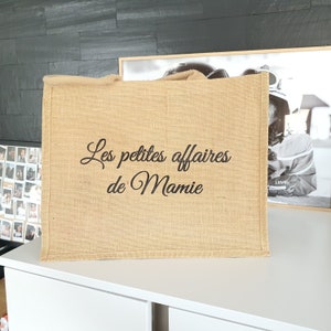 Peut inclure: Un sac cabas en toile de jute marron avec le texte "Les petites affaires de Mamie" brodé en noir.
