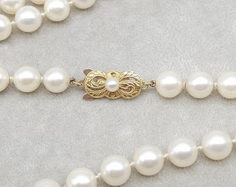 May include: A classic pearl necklace with a gold clasp. The necklace features multiple strands of round, creamy white pearls. The clasp is ornate, with a central pearl accent. The pearls are evenly sized and strung together.