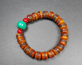 May include: A brown wooden beaded bracelet with a turquoise and red bead accent. The bracelet is made of round beads with a textured surface.