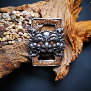 May include: A silver and brown metal decorative door knocker with a lion's head design. The knocker is mounted on a wooden surface.