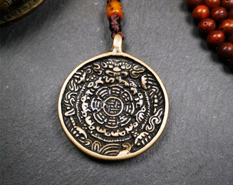 Puede incluir: Un collar con un colgante redondo de color dorado, adornado con un diseño intrincado que presenta un patrón circular con caracteres chinos y un motivo de dragón. El colgante está unido a un cordón marrón con una pequeña cuenta naranja.