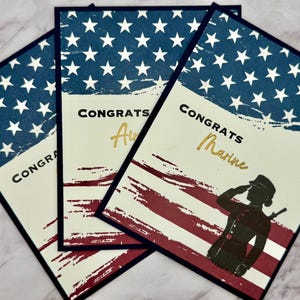 Könnte beinhalten: Drei Grußkarten mit patriotischem Thema. Jede Karte hat einen blauen Hintergrund mit weißen Sternen, rot-weißen Streifen und dem Wort "Congrats" in Schwarz. Eine Karte sagt "Marine" in Gold.