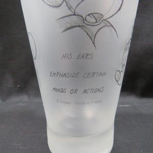 Op de afbeelding: Een matglas met een potloodschets van een stripfiguur. De tekst "HIS EARS EMPHASIZE CERTAIN MOODS OR ACTIONS" staat op het glas. De onderkant van het glas luidt "&copy; Disney Made in France."