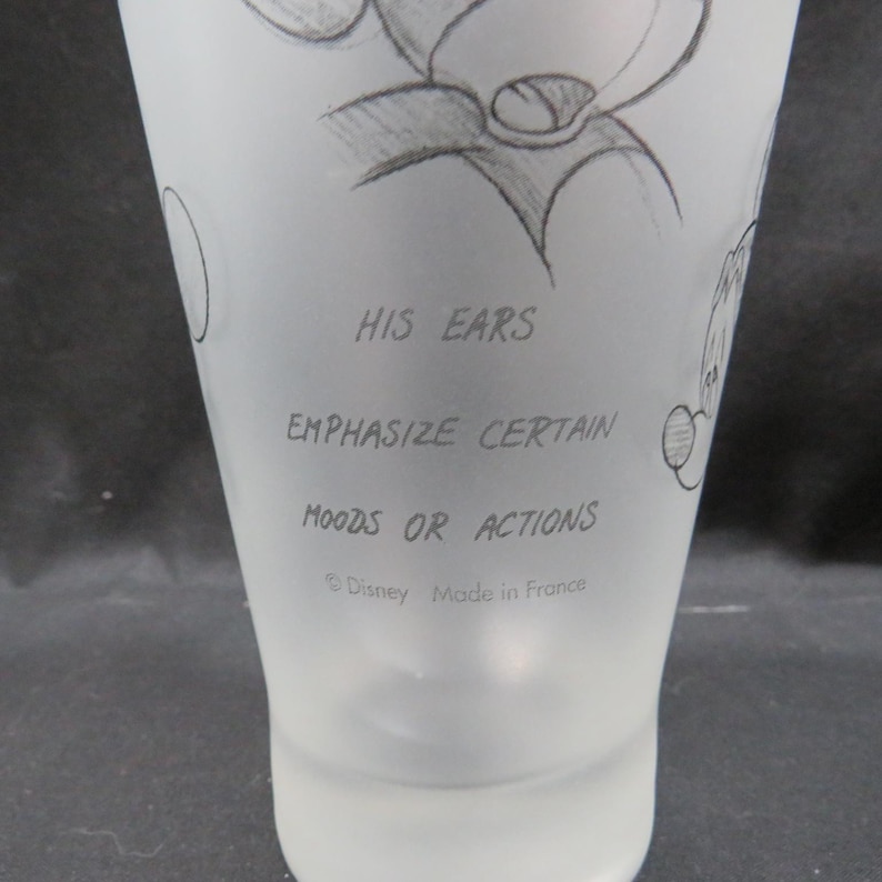 Op de afbeelding: Een matglas met een potloodschets van een stripfiguur. De tekst "HIS EARS EMPHASIZE CERTAIN MOODS OR ACTIONS" staat op het glas. De onderkant van het glas luidt "&copy; Disney Made in France."
