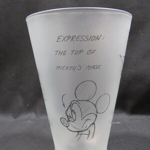 Op de afbeelding: Matte glazen beker met een schets van Mickey Mouse. De beker heeft de tekst "EXPRESSION: THE TOP OF MICKEY'S MASK" in een handschrift. Het ontwerp bevat een schets van Mickey's gezicht.