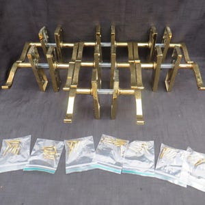 May include: A collection of gold-colored door handles and hardware. The handles are arranged in a row, with several small bags of screws below. The handles have a sleek, modern design, and the hardware appears to be new.