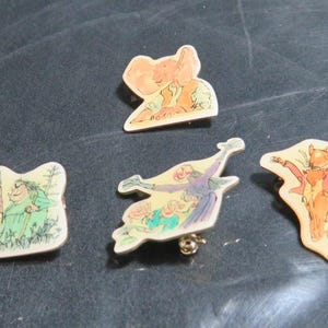 Peut inclure: Cinq épingles en émail colorées représentant des personnages du livre pour enfants 'Où est-ce que les choses sauvages sont'. Les épingles représentent une chose sauvage avec de grandes oreilles, une chose sauvage avec une couronne, une chose sauvage avec une écharpe rouge, une chose sauvage avec une écharpe bleue et une chose sauvage avec une écharpe verte.