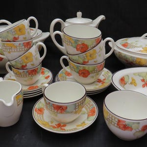 Könnte beinhalten: Ein Vintage-Tee-Set mit einem floralen Muster mit gelben, roten und grünen Blumen. Das Set enthält eine Teekanne, eine Milchkännchen, eine Zuckerdose, Tassen, Untertassen und eine Servierplatte.