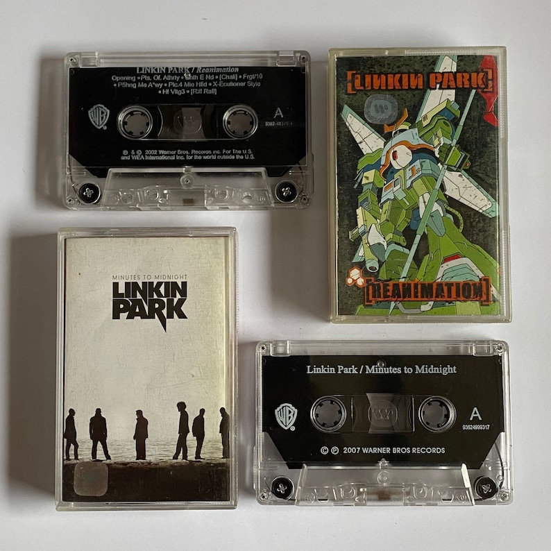 以下が含まれることがあります： リンキン・パークの カセットテープ 4 本。テープは透明なプラスチックケースに入っていて、黒いラベルが付いています。ラベルにはバンド名とアルバムタイトルが書かれており、"Reanimation"、"Minutes to Midnight"、"Linkin Park" などがあります。