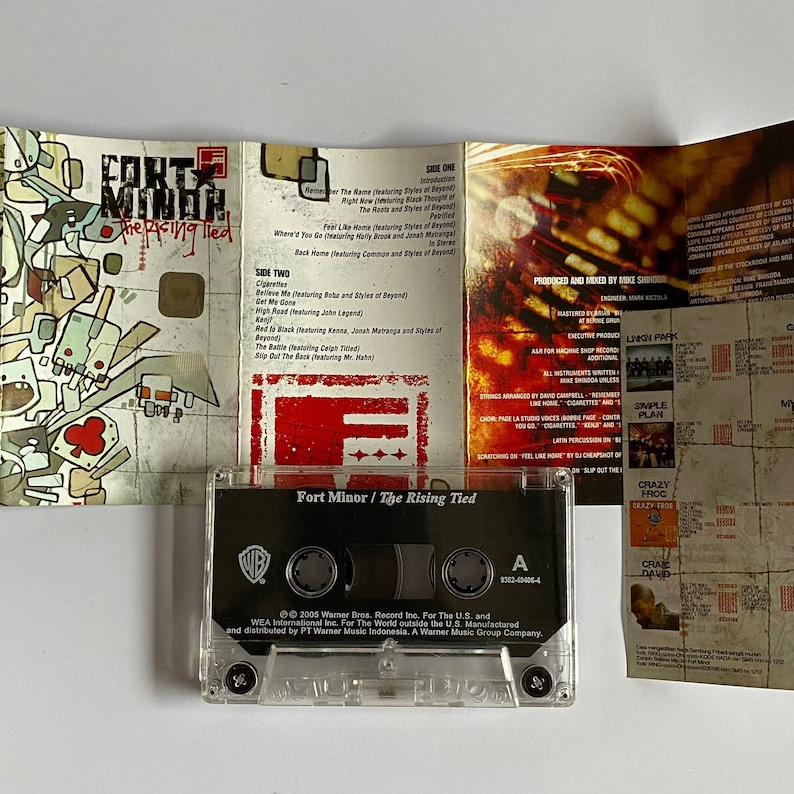 以下が含まれることがあります： 透明なカセットテープケースで、黒いラベルには「Fort Minor / The Rising Tied」と書いてあります。ラベルにはワーナー・ブラザース・レコードのロゴとアルバムの著作権情報も含まれています。