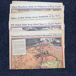 May include: A stack of vintage newspapers with headlines such as "Where Showdown Battle for Philippines Is Being Fought" and "Desperate Nazis Make Last Stand in Mountains of Bavaria." The newspapers have a sepia tone and are on a dark background.