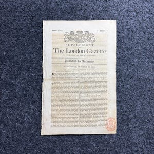 May include: A vintage paper supplement to The London Gazette, dated Wednesday, October 16, 1811. The document features a royal crest at the top, printed text in columns, and a small red circular stamp in the bottom right corner on aged paper.
