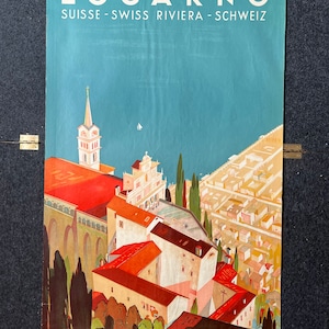 May include: A vintage travel poster advertising the Swiss town of Locarno, featuring a colorful illustration of the town's architecture, including a church with a tall spire, and a view of the lake and surrounding mountains. The poster text reads "Locarno, Suisse - Swiss Riviera - Schweiz".