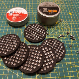 May include: Five round black and silver pellet trays with a total of 250 pellets. Two tin containers of pellets, one labelled "Exact Diablo Airgun Pellets" and the other labelled "RWS Superdome Field Line 500 4.5 mm Cal. 22".