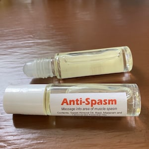 May include: A clear glass roller bottle with a white cap and a white label that reads "Anti-Spasm" and lists the ingredients: Sweet Almond Oil, Basil, Marjoram and Lemongrass Essential Oils. Massage into area of muscle spasm.