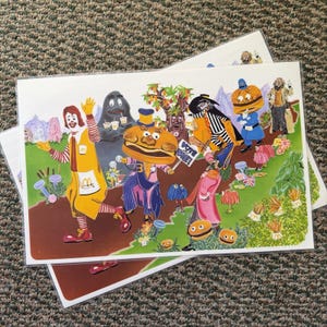 May include: A colorful illustration print featuring Ronald McDonald, Grimace, Mayor McCheese, and the Hamburglar in a whimsical outdoor setting. The artwork includes a sign that reads VOTE FOR ME and various McDonald's themed characters and icons.