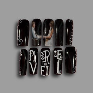 May include: Black press-on nails with white swirls and a wedding photo design. The phrase "PIERCE THE VEIL" is written in white on some nails. A set of ten artificial nails.