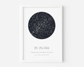 May include: A framed vertical print featuring a circular dark navy star map with white constellations. Below the circle, the text reads: Mr + Mrs Roberts, MARRIED UNDER THESE STARS | 18TH OF JUNE, 2022, ROYAL BOTANICAL GARDENS, SYDNEY.