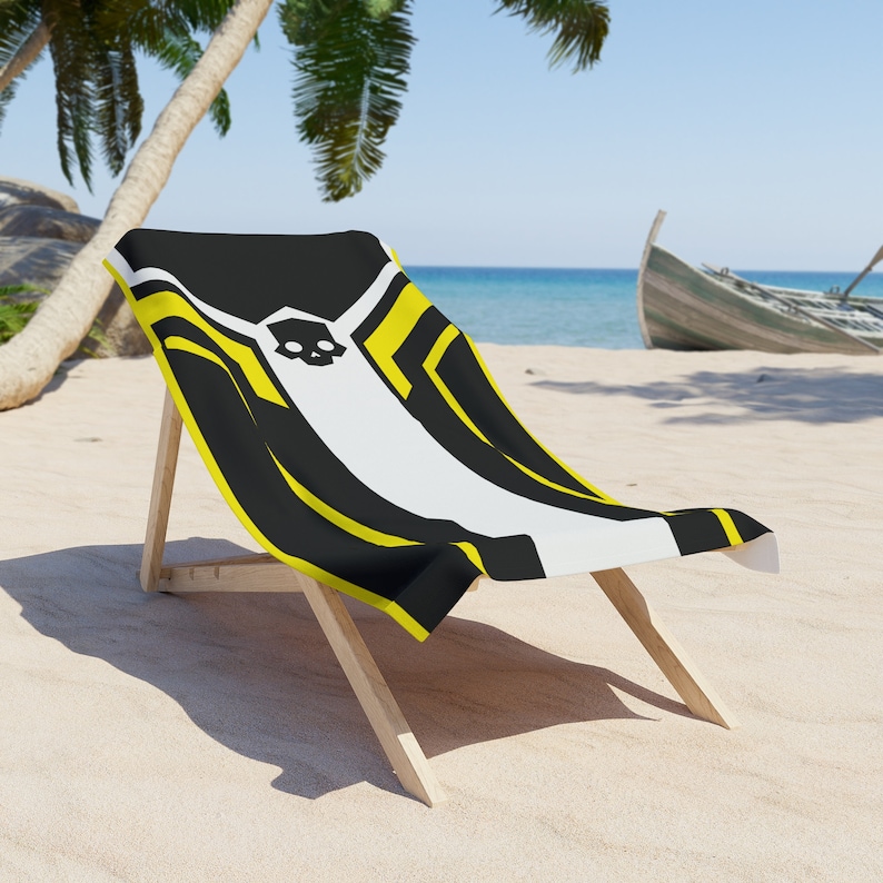 Puede incluir: Una silla de playa a rayas negras y amarillas con un dise&ntilde;o de calavera. La silla es de madera y tiene un asiento de tela blanca. La silla est&aacute; en una playa de arena con palmeras en el fondo.