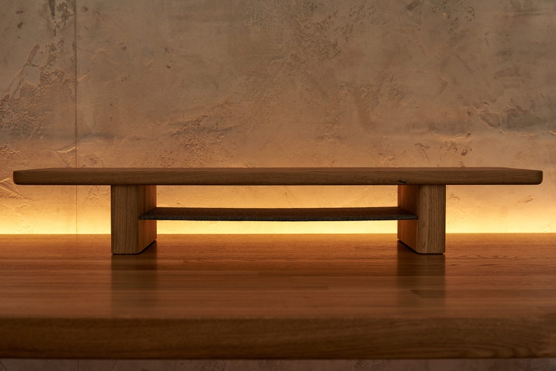 May include: A wooden shelf unit with two shelves. The shelf is made of natural wood and has a simple, modern design.