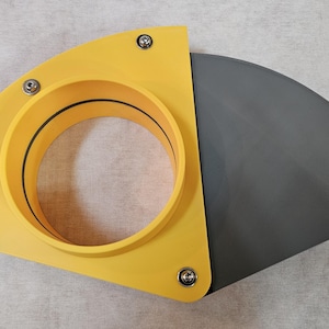 May include: A yellow and gray plastic component with a circular opening and a curved, fan-like section. The yellow portion has a circular opening and is secured with screws. The gray section is a flat, curved piece.