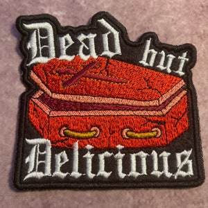 Broderad lapp med texten "Dead But Delicious" 10 cm bred