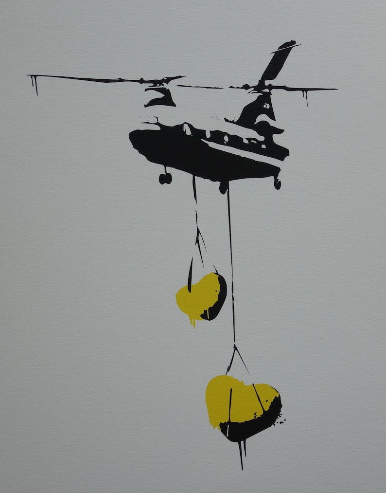 May include: A black silhouette of a helicopter carrying two yellow, heart-shaped objects.