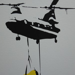 May include: Black and white silhouette of a helicopter carrying a yellow object.